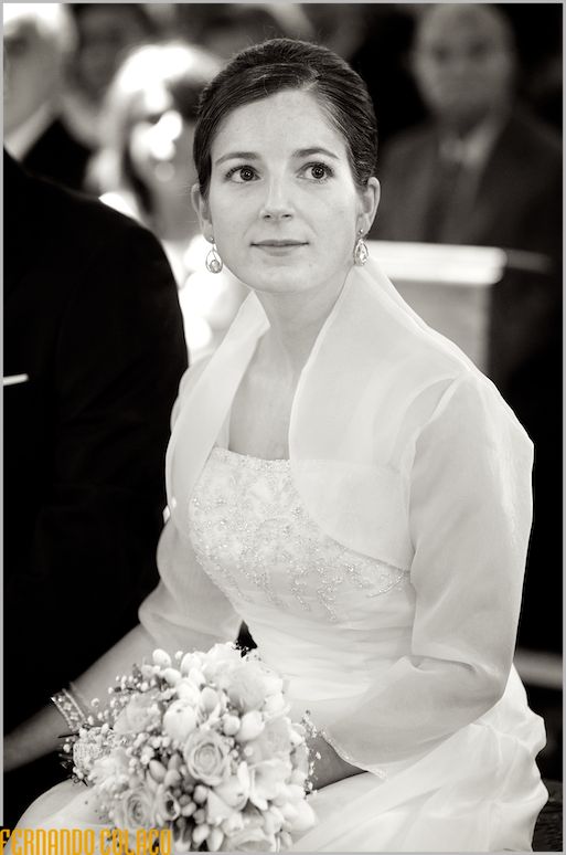 A noiva, sentada e de bouquet na mão, olha com atenção para o padre, fora da fotografia, durante a homilia, conforme a viu o fotógrafo de casamento em Lisboa.