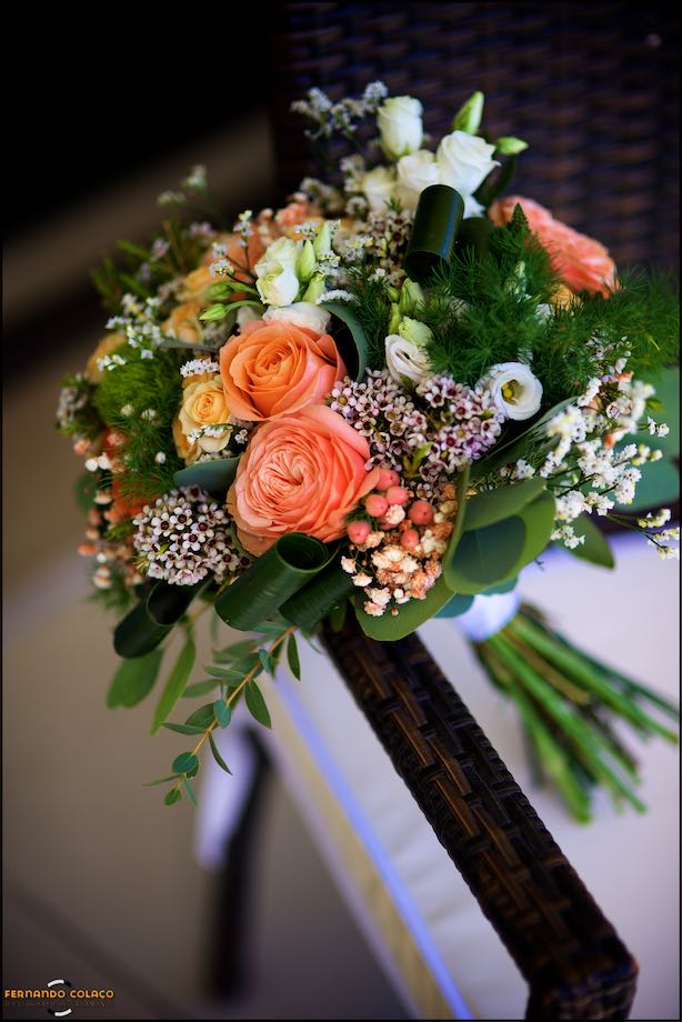 O ramo da noiva com rosas de várias cores e tamanhos entre outras flores, sobre uma cadeira no Grande Real Villa Itália Hotel & Spa, pelo fotógrafo de casamento em Cascais.