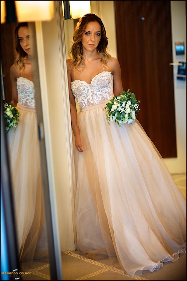 Com o bouquet na mão a noiva encosta-se junto de um espelho que a reflecte, captada pelo fotógrafo de casamento em Cascais momentos antes de sair do Grande Real Villa Itália Hotel & Spa para a cerimónia do casamento.