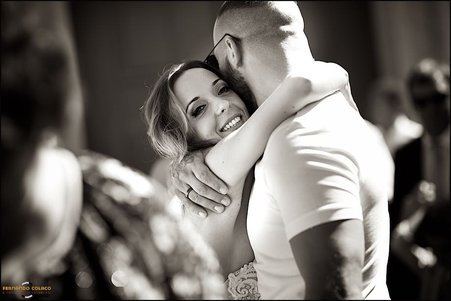 A noiva, já fora da igreja quando acabou a cerimónia do casamento, abraça um amigo que lhe dá os parabéns, vistos pelo fotógrafo de casamento em Cascais.