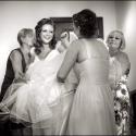 The bride laughs with joy as three friends help her put on her dress for the ceremony at the Palácio Estoril Hotel, Golf & Wellness, in a moment captured by the wedding photographer in Cascais.