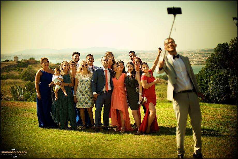 Um grupo de convidados do casamento nos Pézinhos no Tejo tira uma selfie, vistos pelo fotógrafo de casamento em Almada.