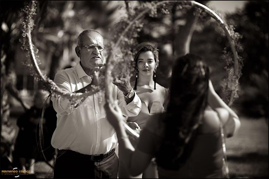 Vistos  pelo fotógrafo de casamento em Almada, um convidado do casamento tira uma fotografia a alguém por entre círculos decorados com flores na Quinta Pézinhos no Tejo.