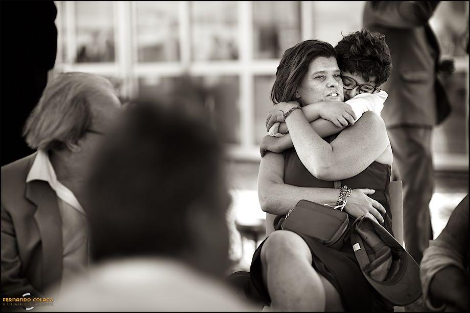 Durante o convívio a seguir à cerimónia do casamento na Quinta Pézinhos no Tejo, um menino abraça a sua mãe pelo pescoço, com ternura, captados pelo fotógrafo de casamento em Almada.