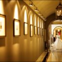 At the bottom of a corridor of the Palácio Estoril Hotel, the bride waits to enter the wedding ceremony room, captured by the wedding photographer in Cascais.
