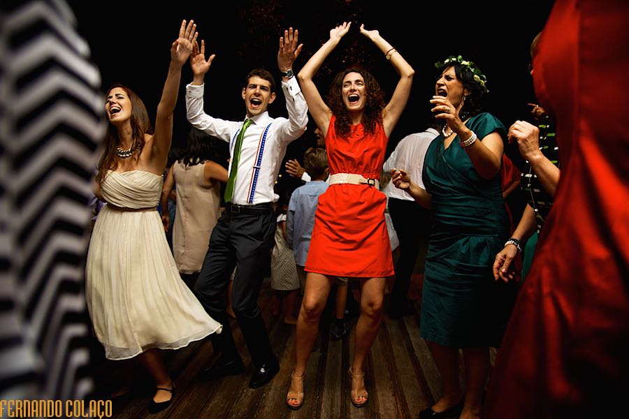 Wedding guests in choreographed arms in the air, on the dance floor of the wedding party, seen by the wedding photographer in Lisbon.