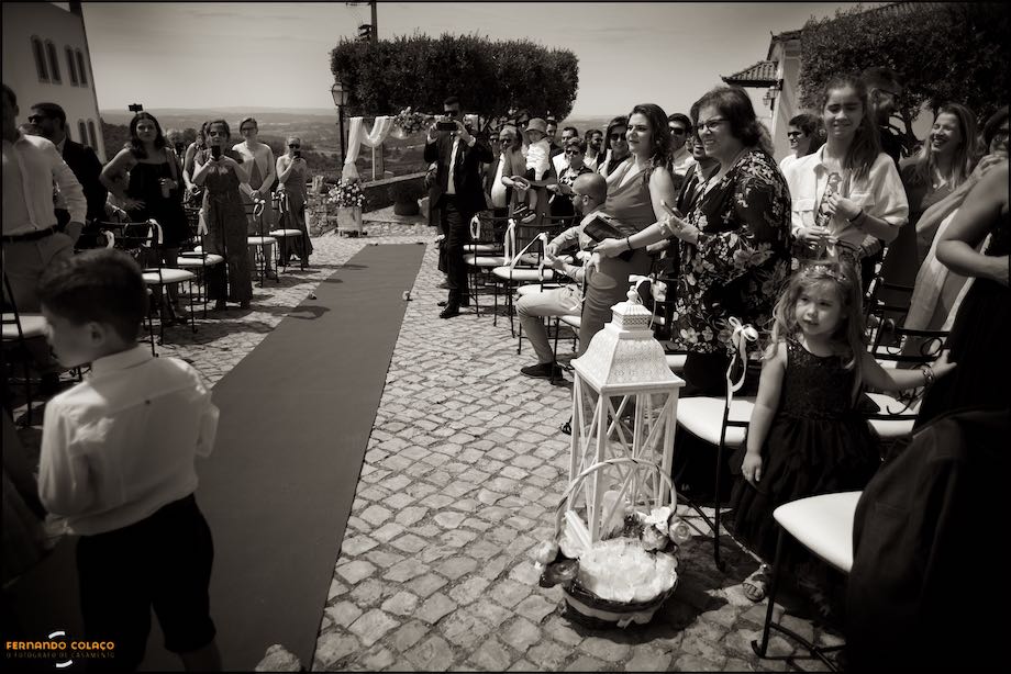The red carpet for the bride to walk to the ceremonial table flanked by the guests waiting for her, in a composition by the Lisbon wedding photographer at Quinta do Castro in Cadaval.