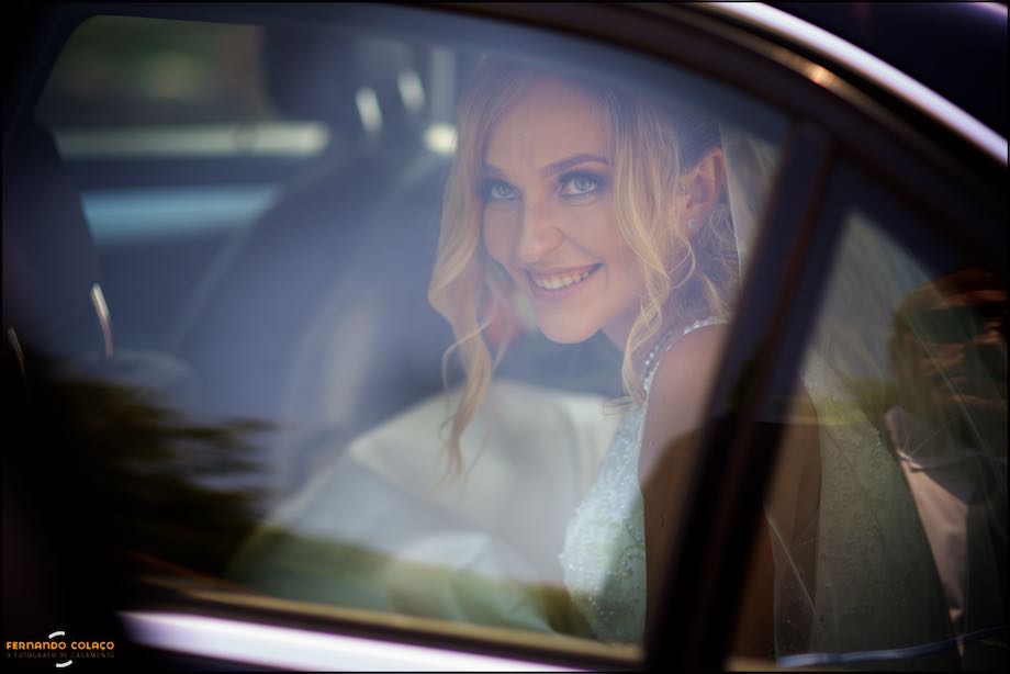The bride is seen through the car window as she arrives at Quinta do Castro in Cadaval for the ceremony, in a composition by the Lisbon wedding photographer.