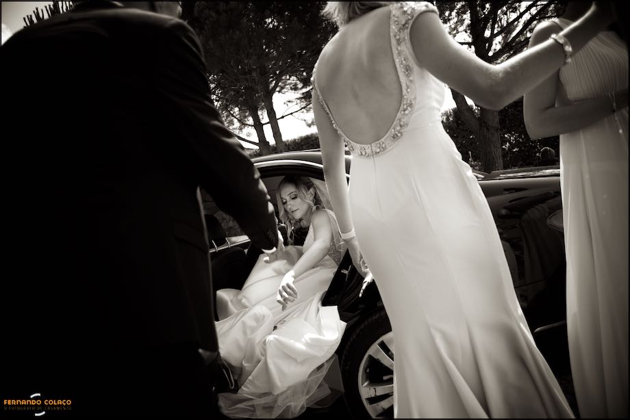 The bride exits the car, framed by her father and two friends, as she arrives at Quinta do Castro for the ceremony, captured by the wedding photographer in Lisbon.