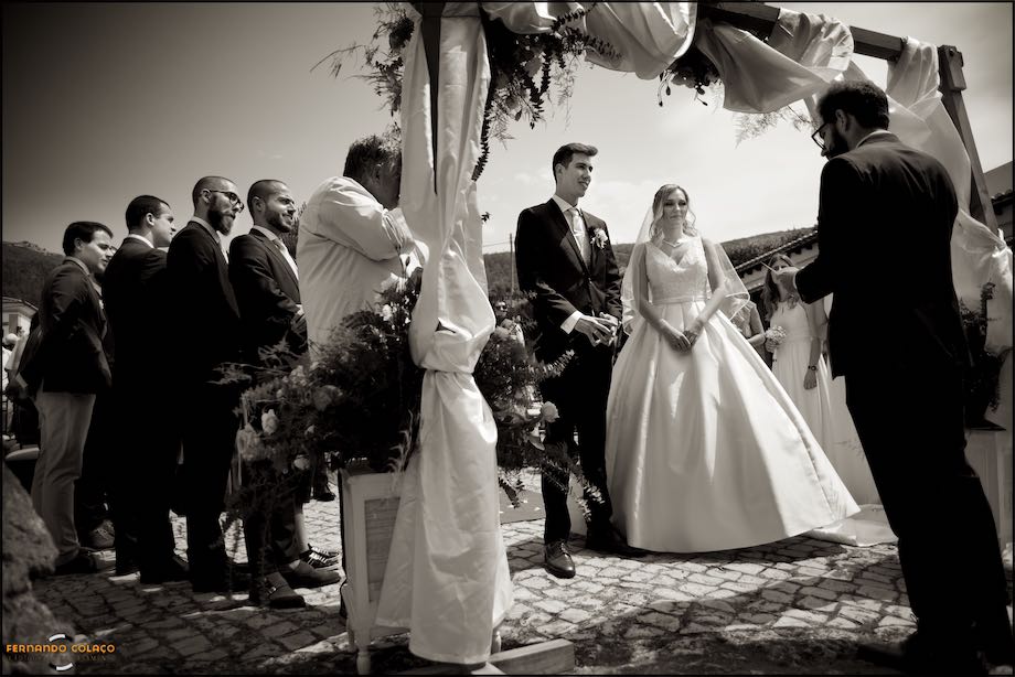 The bride and groom flanked by the officiant of the ceremony and friends of the groom, during the wedding ceremony at Quinta do Castro in Cadaval.
