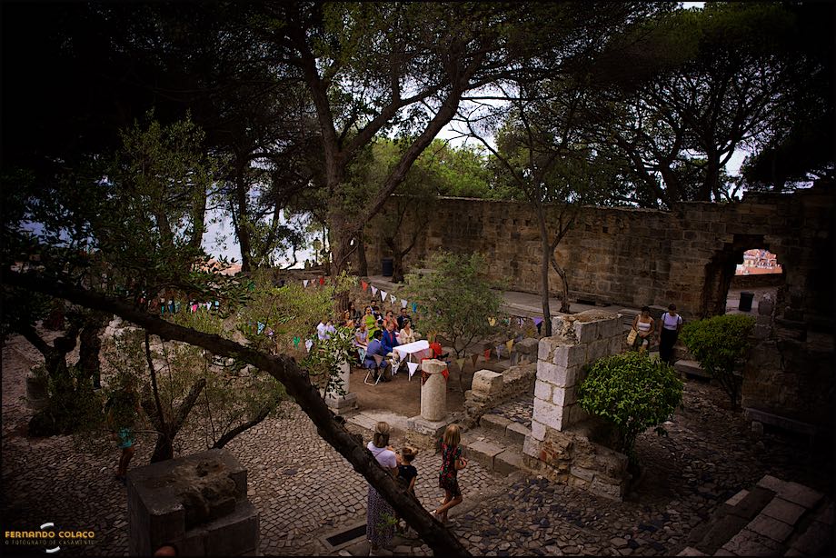 View from above and away from the ceremony site at St. George's castle in Lisbon, through ancient trees and walls, seen by the wedding photographer in Lisbon.