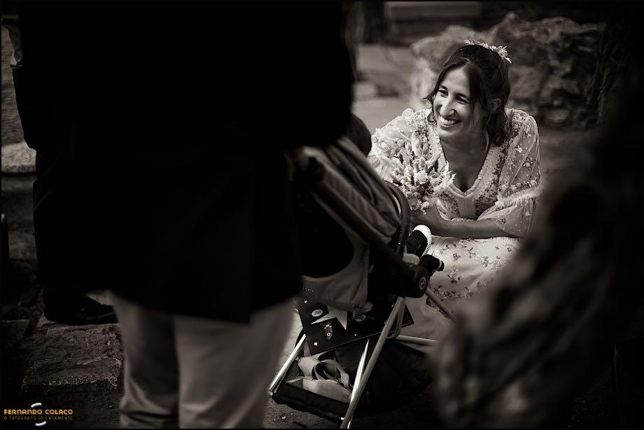 The bride below gives a cuddle to her nephew sitting in a baby seat, seen by the wedding photographer in Lisbon.