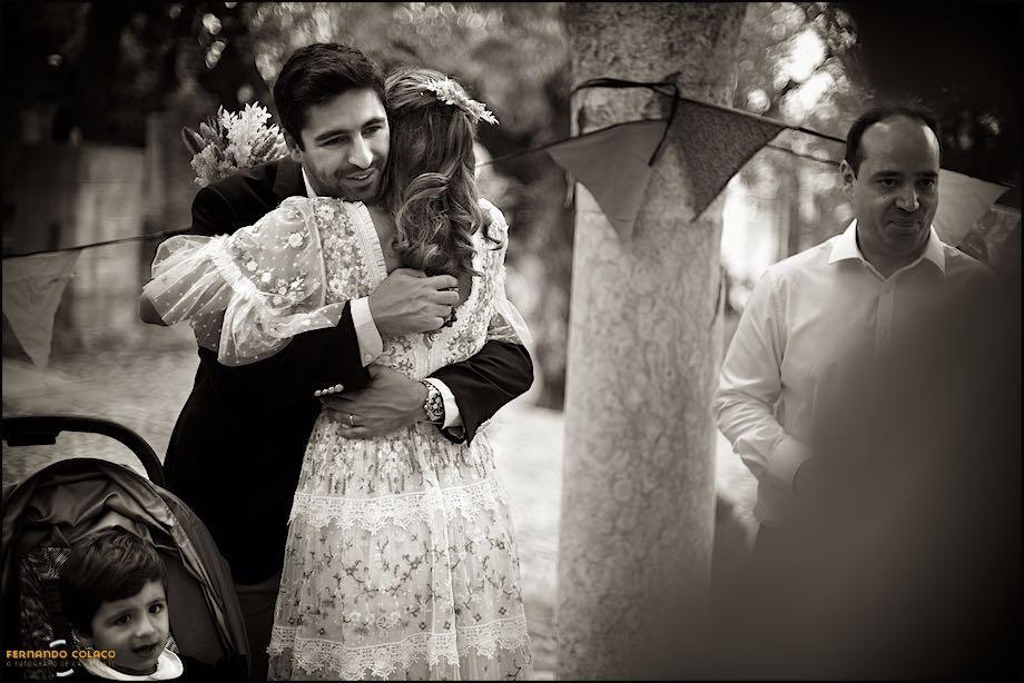 The bride hugs her brother-in-law with her nephew, below, sitting in the baby car seat and a relative on the right, seen by the wedding photographer in Lisbon.