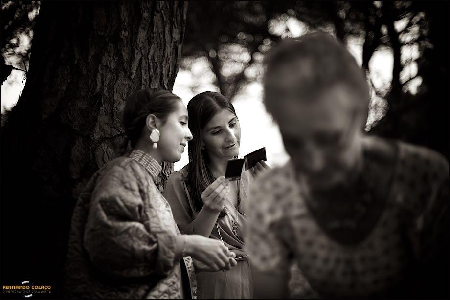 The bride's sister shows instantaneous photos to a friend that she took during the get-together after the ceremony, seen by the wedding photographer in Lisbon.
