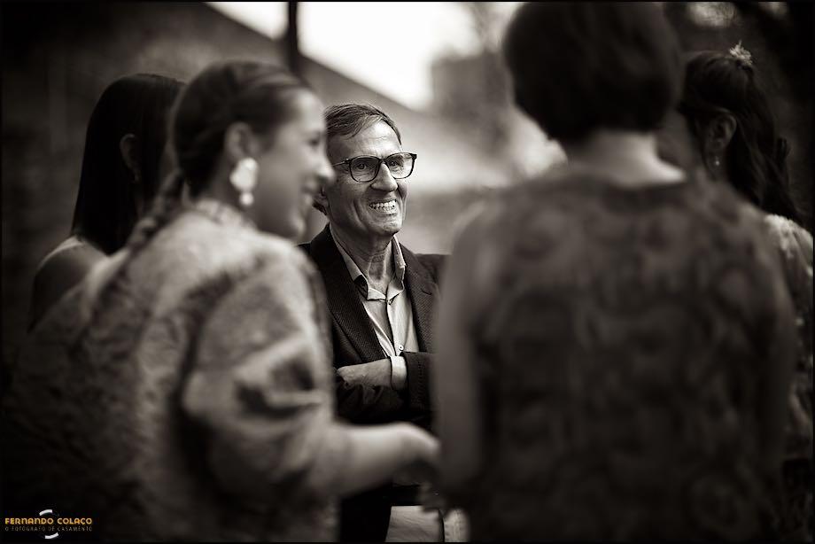 Amongst the bride's family members, her father laughs during the conversation they are having at the get-together before leaving for the celebratory wedding meal.