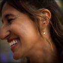 The face of the bride, seen in profile, laughing with joy at the gathering after the wedding ceremony, showing the wedding photographer in Lisbon the earring.