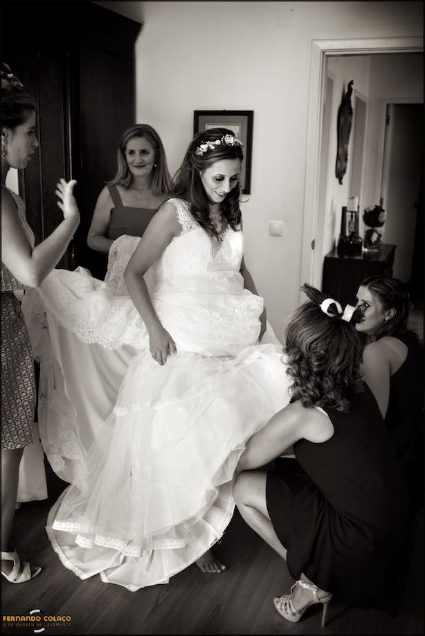 The bride is in the center of a wheel with her mother and three friends helping her with her dress, captured by the wedding photographer in Sintra.