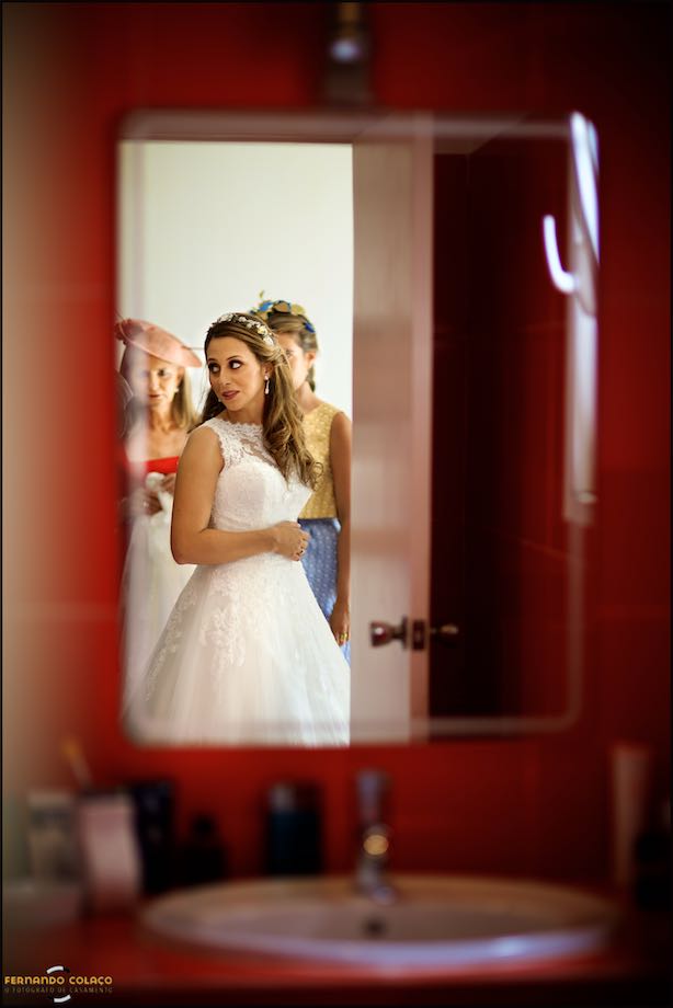 In a mirror up high, the Sintra wedding photographer saw the bride in front of her mother and a girl friend who check if the dress is well placed.