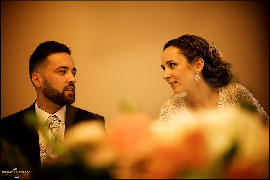 The bride and groom celebrate with champagne as soon as they sit down at the table for their wedding meal at the Vila Galé Collection Palácio dos Arcos Hotel, as seen by their wedding photographer in Lisbon.