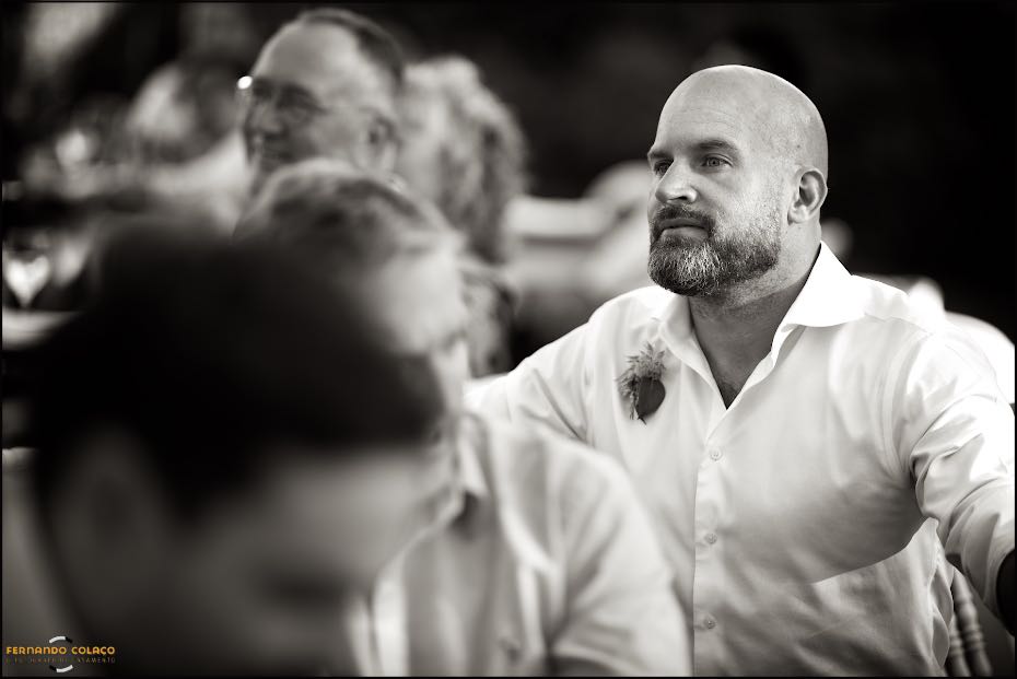 A guest listens attentively to a speech during dinner in Agostos, captured by the wedding photographer in the Algarve.