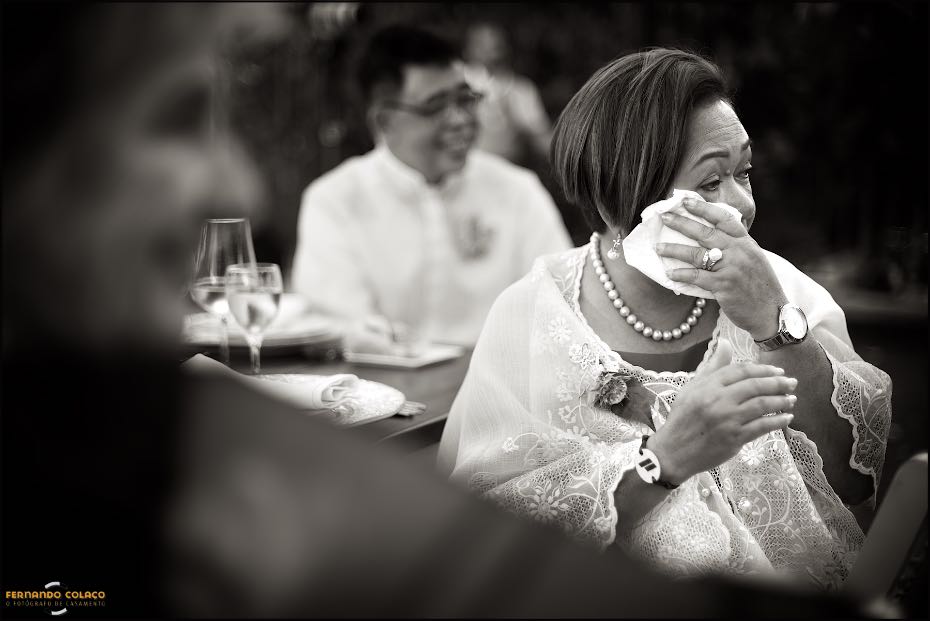 The mother of the bride wipes her tears with a handkerchief after being moved by a speech during dinner at Agostos, as seen by the wedding photographer in the Algarve.