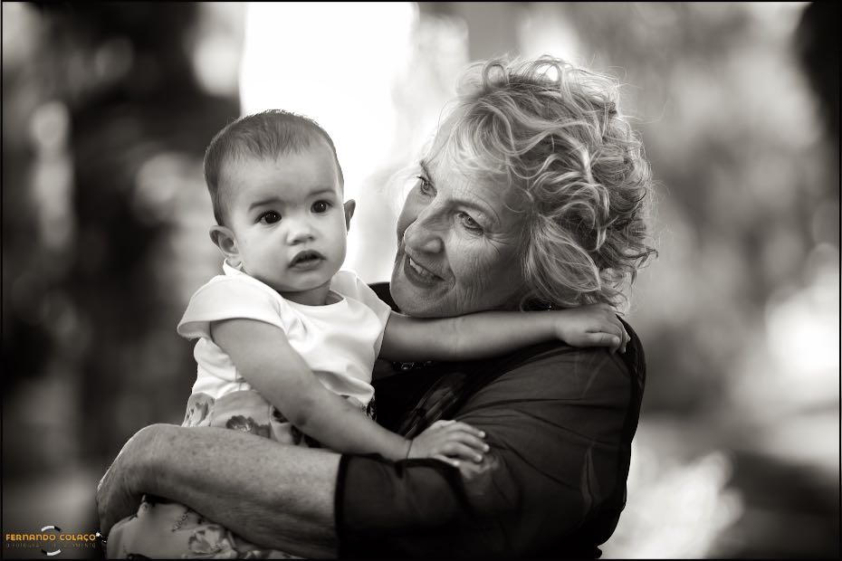 On her grandmother's lap, the bride and groom's daughter feels as comfortable as possible, as seen by the wedding photographer in Agostos, Algarve.