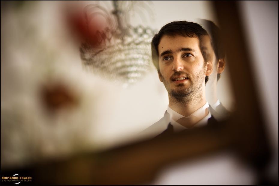 The groom's face, in a photo taken by the wedding photographer in Évora, between flowers and a candelabra, both out of focus.
