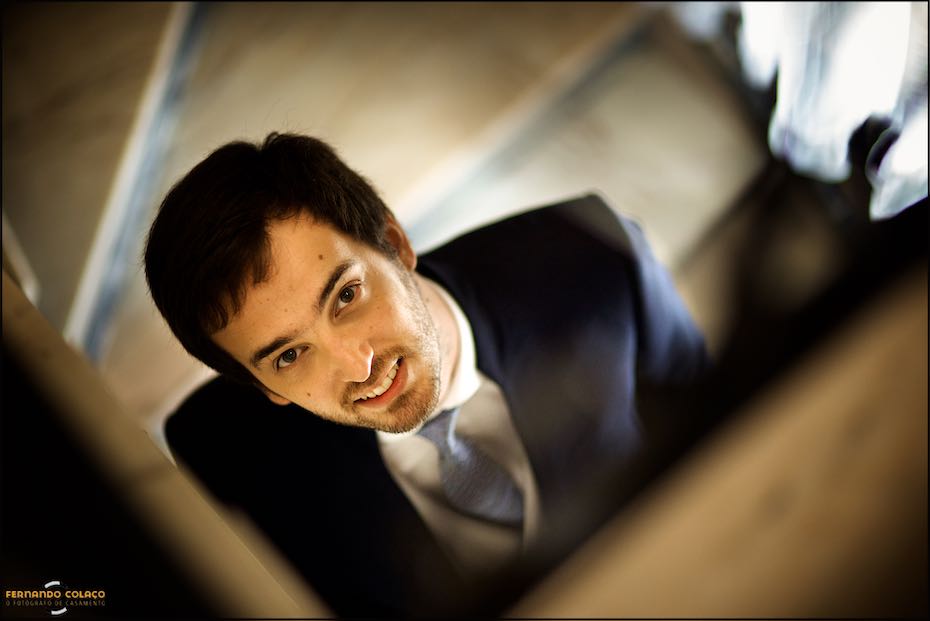 The groom's face looking up as he descended the stairs, captured by the wedding photographer in Évora.
