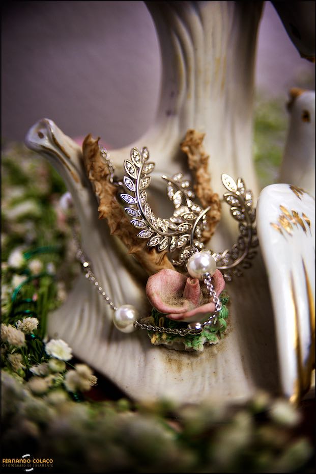 The bride's earrings and necklace on a piece of porcelain and flowers, as seen by the wedding photographer in Évora.