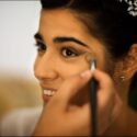A hand with a brush sprinkles powder on the bride's face as she prepares for her wedding at the Igreja Matriz in Reguengos de Monsaraz, in a portrait by a wedding photographer in the Alentejo.