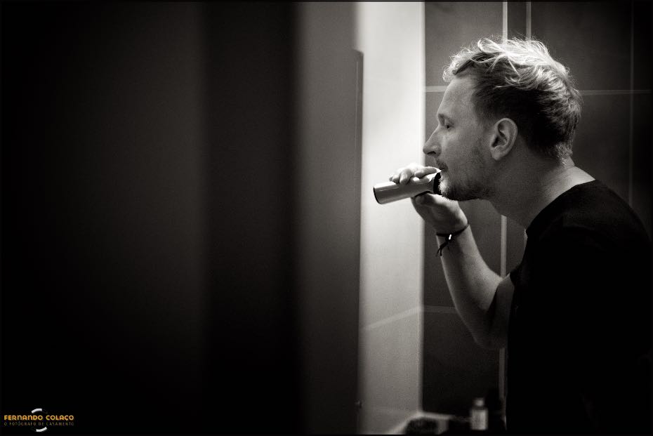 Visto de fora, o noivo barbeia-se ao espelho da casa de banho, numa composição do fotógrafo de casamento no Algarve.