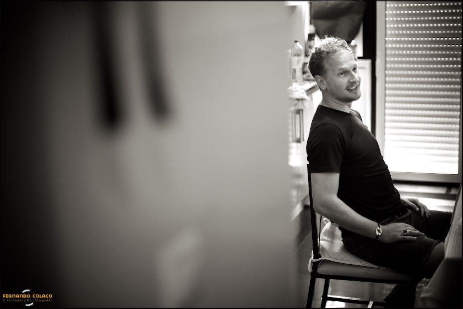 O noivo, sentado e bem disposto, conversa com alguém antes de começar a preparar-se para a cerimónia na igreja de S. Lourenço em Almancil.