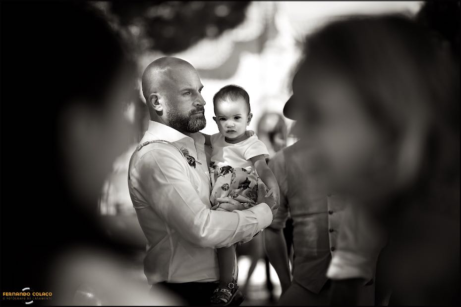Ao colo do esmerado tio, vistos por entre os convidados, a bebé filha dos noivos sentiu-se sempre segura durante a festa do casamento nos  Agostos, no Algarve.
