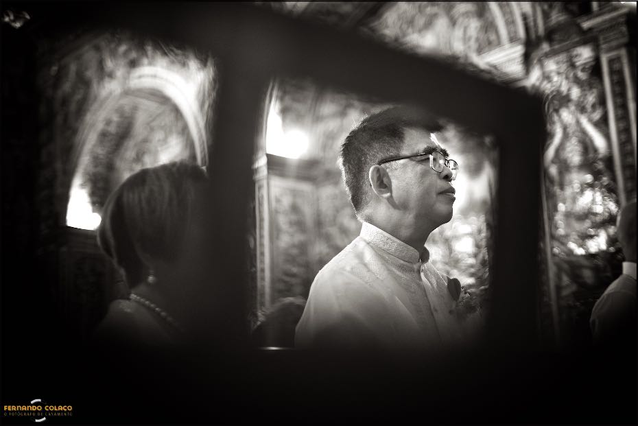 O pai da noiva, visto por entre as aberturas de um móvel da igreja de S. Lourenço, em Almancil, pelo fotógrafo de casamento no Algarve.