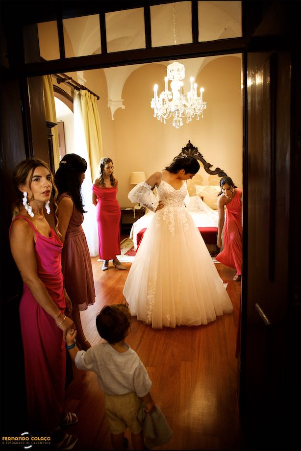 Noiva, com as amigas, a finalizar o vestir do vestido e pronta para a cerimónia do casamento no Convento do Espinheiro em Évora.