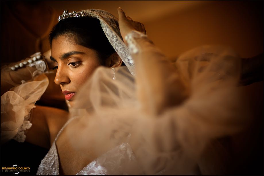 Rosto da noiva a segurar o véu que está ser preso ao cabelo, antes da cerimónia na Igreja do Convento do Espinheiro em Évora.
