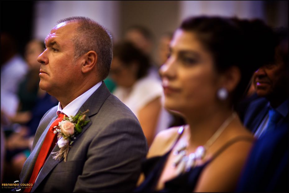 Ao lado da esposa, desfocada, o pai da noiva escuta com atenção a cerimónia do casamento na igreja Matriz de Reguengos de Monsaraz.
