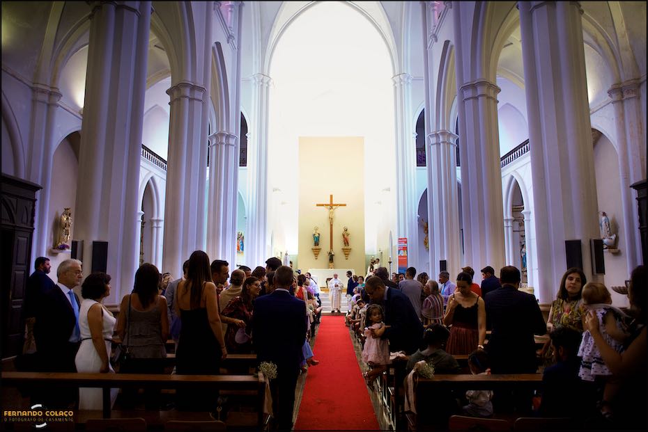 Vista da Igreja Matriz de Reguengos de Monsaraz com os convidados e o noivo com a padre, junto do altar à espera da noiva para a cerimónia do casamento.