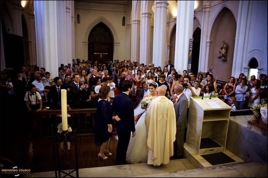 Igreja Matriz de Reguengos de Monsaraz cheia de convidados, quando a noiva chega junto do noivo no altar para a cerimónia do casamento.