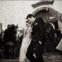 O noivo e a noiva quando saem da cerimónia do casamento por entre os convidados que lhes atiram tiras de papel colorido.