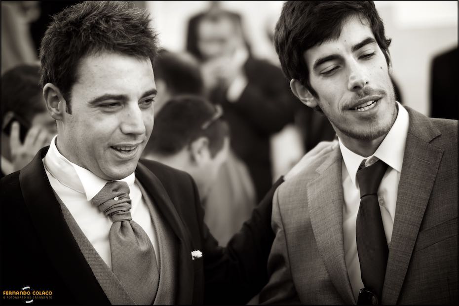 O noivo em conversa com um amigo que lhe dá os cumprimentos depois da cerimónia do casamento.