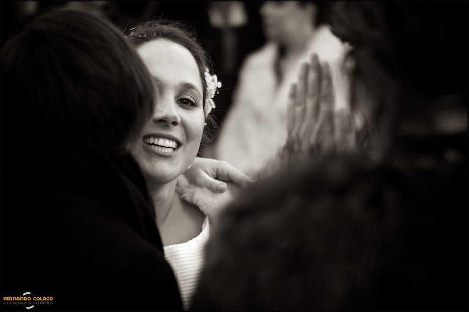 O rosto da noiva, muito feliz, entre os convidados que, à saída da igreja, a felicitam pelo casamento.