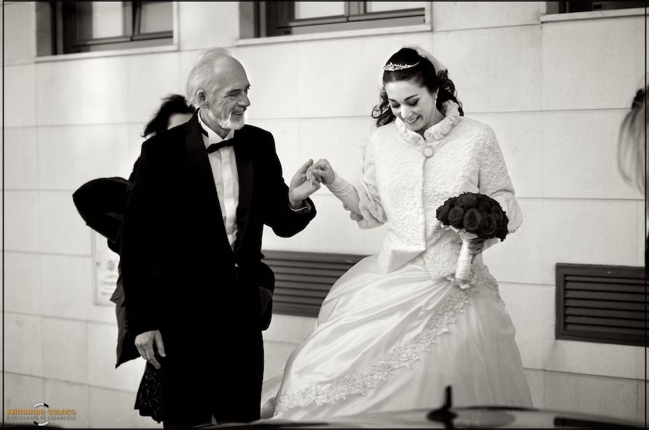 A noiva sai de casa, para partir para a cerimónia, de mão dada com o seu pai que a ajuda, vistos pelo fotógrafo de casamento em Almada.