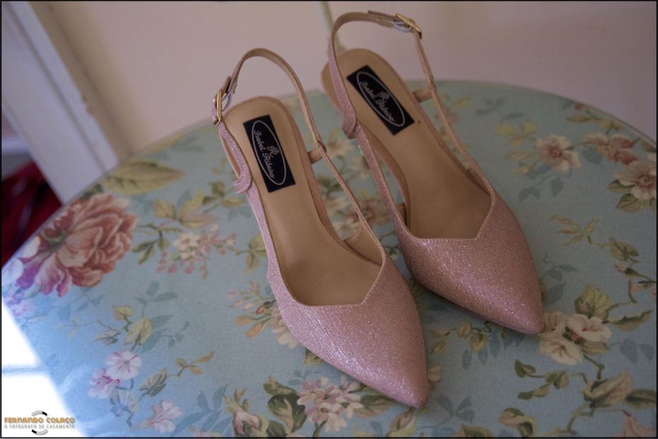 Sapatos da noiva sobre o tampo de uma mesa decorada a azul com ramos de flores.