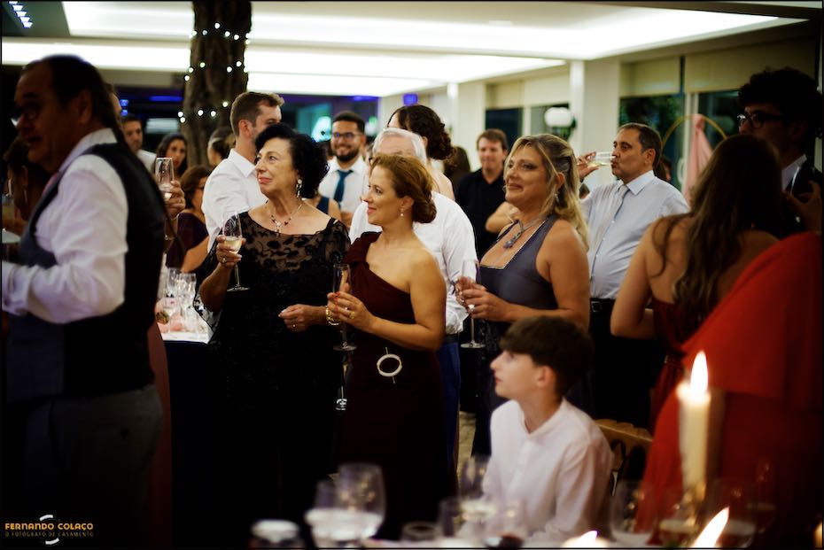 Convidados do casamento olham com a atenção para os noivos, enquanto eles cortam o bolo do casamento na Quinta do Pé da Serra em Sintra.