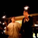 The bride and groom look at each other with sticks of fire in their hands on their way to the cake cutting at Casa de Reguengos, by the wedding photographer in Lisbon.
