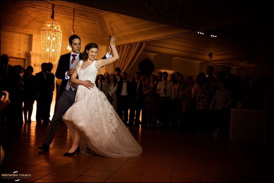 The groom holds the bride's hand as she performs part of the opening dance at the Casa de Reguengos wedding party.