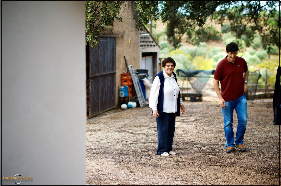 Next to the storeroom on his parents' farm, the groom talks to his mother before starting to get ready for his wedding day.