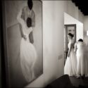 Next to a large door, a friend of the bride's clutches her dress, and a large painting can be seen on the wall of a couple dancing, as seen by the wedding photographer in Lisbon.
