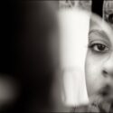 Eye and part of the bride's face in a round mirror as she checks her hairstyle, composed by the wedding photographer in Almada.